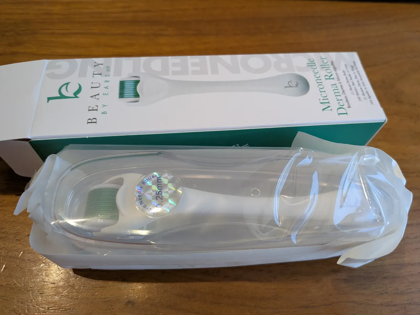 Opened dermaroller box showing the roller in its sterile blister tray — the holographic seal sticker on the head clearly marks needle length (in this case 0.25 mm, too short for AGA)