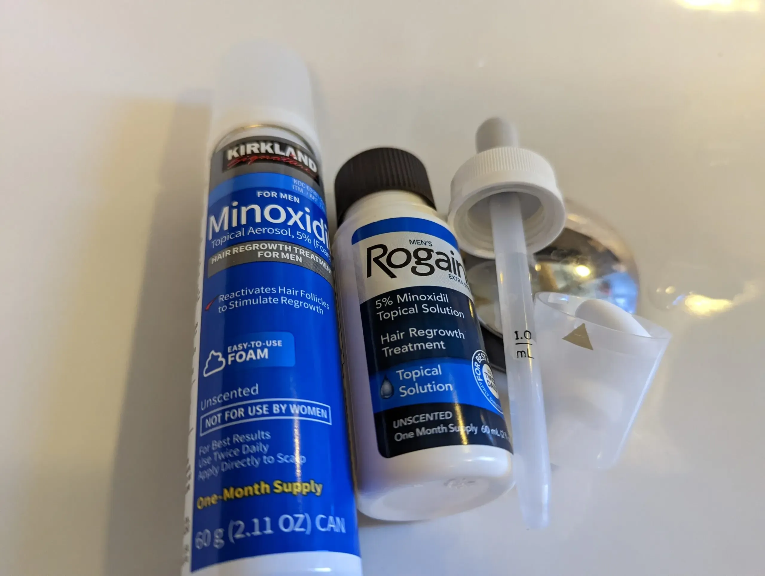 Texture comparison: Kirkland Minoxidil foam (left, mousse-like consistency) vs liquid solution (right, watery dropper-applied) — same active drug, very different application experience